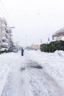 Atina 'da bir kar fırtınası sırasında, Yunanistan' ın başkenti Avrupa 'da, Vrilissia bölgesinde kar yağdı. Sokakta bir adam yürüyor..
