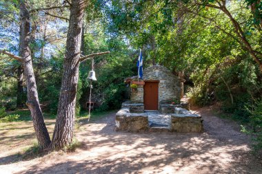 Güneşli bir günde dağ ormanlarında küçük, ortodoks, taş gibi bir Hıristiyan kilisesi. Penteli, Yunanistan.