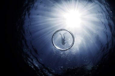A Diver circled by bubble ring inside of a Snell's Window with Sun beams behind them clipart
