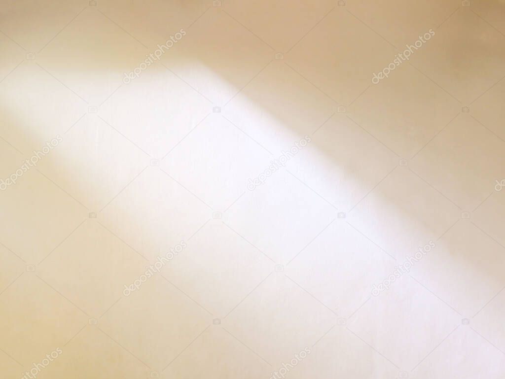 Warm beige plastered wall illuminated by sunlight with window shadow
