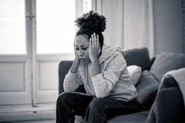 Genç ve çekici Afro-Amerikalı kadın oturma odasındaki kanepede uzanıyor üzgün ve endişeli hissediyor depresyon, sıkıntı ve endişe içinde zihinsel sağlık sorunları ve kırık kalp konsepti.