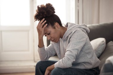 Depresyondaki genç ve çekici Afro-Amerikalı kadın evdeki kanepede uzanmış üzgün yorgun ve endişeli hissediyor depresyon, stres ve endişe zihinsel sağlık, yalnızlık ve yalnızlık kavramında.