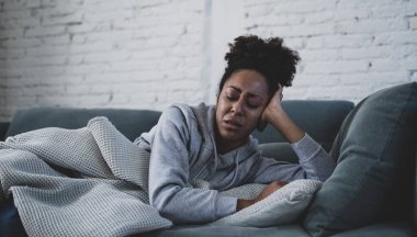 Genç ve çekici Afro-Amerikalı kadın oturma odasındaki kanepede uzanıyor üzgün ve endişeli hissediyor depresyon, sıkıntı ve endişe içinde zihinsel sağlık sorunları ve kırık kalp konsepti.