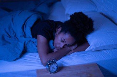 Genç, güzel afro-amerikalı kadın gece geç saatlerde yatağında yatıp uykusuzluk çeken uykusuzluk sorunu çekmeye çalışıyor ya da stresli ve endişeli zihinsel sağlık konsepti gibi görünen kabuslardan korkuyor..