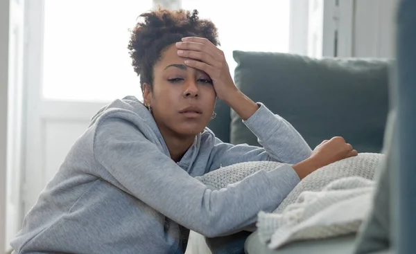 若い魅力的なアフリカ系アメリカ人の女性が自宅のリビングルームのソファに横たわって悲しい疲れと心配苦しみうつ病 精神衛生上の苦痛と不安 問題と壊れた心の概念を感じて — ストック写真