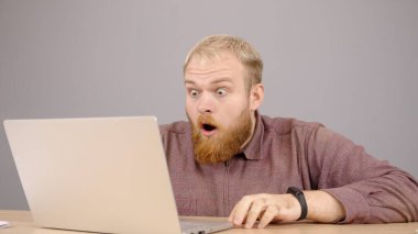 Kafkasyalı üzgün adam laptopunu kullanıyor. Mesajlaşmanın keyfini çıkarıyor.. 