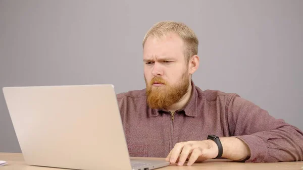 Upset caucasian man is using laptop texting enjoying friendly communication. — Stock Photo, Image