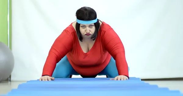 Şişman genç bir kadın yerde spor yapıyor göbek yağları ve kilolarından kurtulmak için.