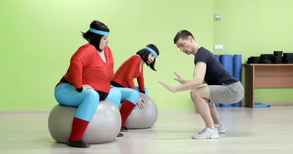 Antrenör spor salonundaki şişman kadına egzersizleri gösteriyor.. 