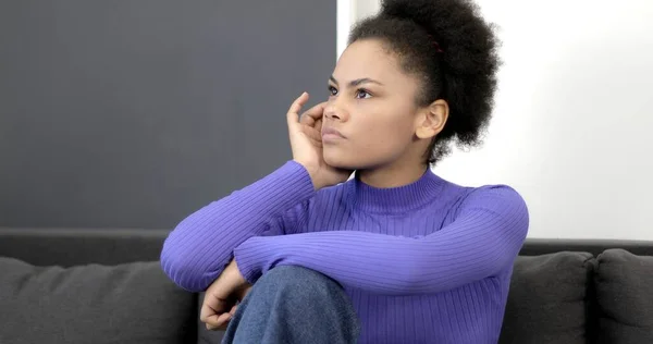 A beautiful black woman is sitting on a sofa and she has an idea. — Stock Photo, Image