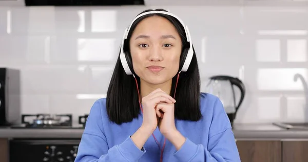 Retrato de uma menina asiática atraente em fones de ouvido falando com a câmera. — Fotografia de Stock