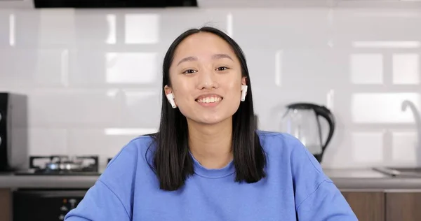 Portrait of an attractive asian girl in headphones talking to the camera. — Stock Photo, Image