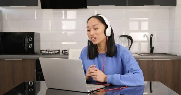 Asian woman wearing headphones studying online — стоковое фото