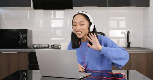 Asyalı kadın kulaklık takıyor ve laptoptan arıyor.