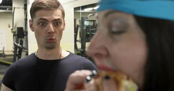 Aç şişman kadın spor salonunda büyük bir hamburger yiyor.. 