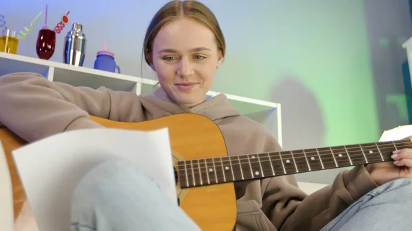 Dreamy girl playing acoustic guitar at home. — Stockfoto