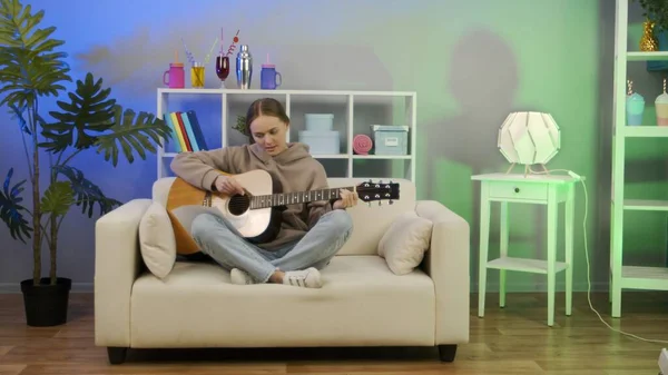 Meisje speelt akoestische gitaar thuis. Stockfoto
