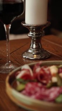 Bir restoranda akşam yemeği, salam, bir bardak kırmızı şarap, bir mum yakılır.