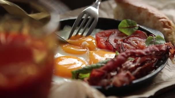 Traditionelles englisches Frühstück aus nächster Nähe. Mädchen schneidet Spiegeleier und taucht Brot in Eigelb — Stockvideo