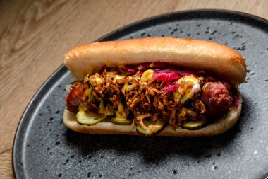 Sosisli sandviç, kızarmış soğan ve salatalık turşusu.