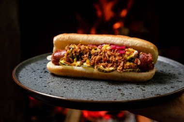 Sosisli sandviç, kızarmış soğan ve salatalık turşusu.