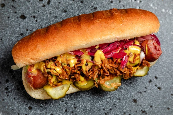 Sosisli sandviç, kızarmış soğan ve salatalık turşusu.