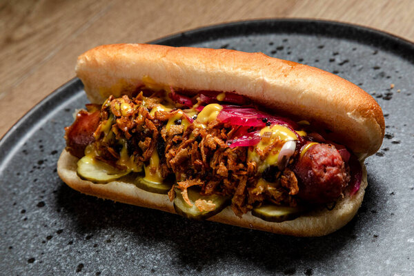 хот-дог с домашней колбасой, луком во фритюре и маринованными огурцами