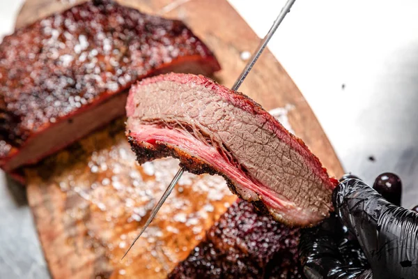 the chef cuts smoked beef cooked in a smokehouse