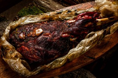 Tütsülenmiş et. Tahta arka planda bir tütsüleme evinde pişirilmiş sığır budu.