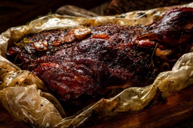 Tütsülenmiş et. Tahta arka planda bir tütsüleme evinde pişirilmiş sığır budu.