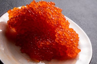 Beyaz tabakta kırmızı havyar, koyu arka plan, lezzetli kırmızı havyar.