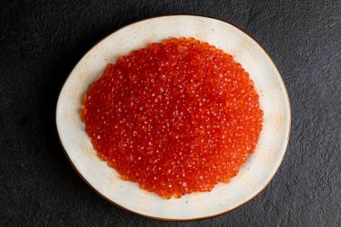 Beyaz tabakta kırmızı havyar, koyu arka plan, lezzetli kırmızı havyar.