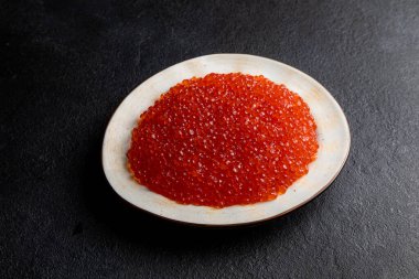 Beyaz tabakta kırmızı havyar, koyu arka plan, lezzetli kırmızı havyar.