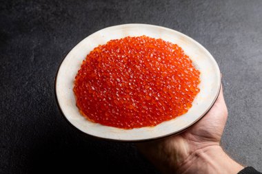 Beyaz tabakta kırmızı havyar, koyu arka plan, lezzetli kırmızı havyar.