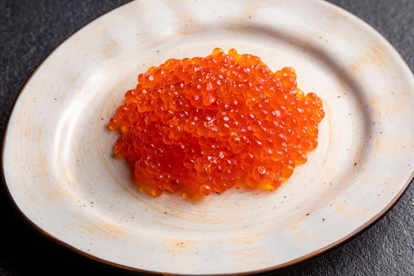 Red caviar on a white plate, dark background, delicacy red caviar — Zdjęcie stockowe