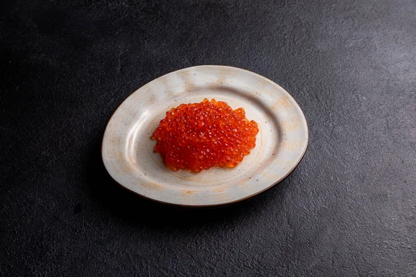 Red caviar on a white plate, dark background, delicacy red caviar — Zdjęcie stockowe