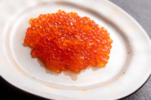 Red caviar on a white plate, dark background, delicacy red caviar — Zdjęcie stockowe