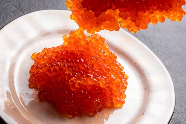 Red caviar on a white plate, dark background, delicacy red caviar — Zdjęcie stockowe