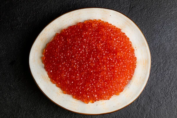 Beyaz tabakta kırmızı havyar, koyu arka plan, lezzetli kırmızı havyar.