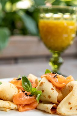 Meyve suyuyla servis edilen taze otlarla süslenmiş somonlu gözleme. Kahvaltı, içteki tabağın fotoğrafı.