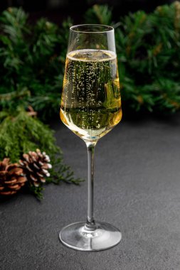 Karanlık bir Noel arkaplanında bir bardak şampanya Noel oyuncakları ve Noel ağacı