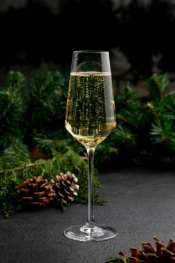 Karanlık bir Noel arkaplanında bir bardak şampanya Noel oyuncakları ve Noel ağacı