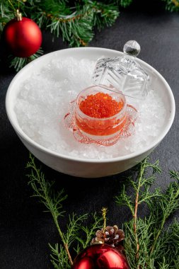 Oyuncak ve dallarla süslenmiş karanlık bir Noel arka planında kırmızı havyar