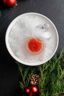 Oyuncak ve dallarla süslenmiş karanlık bir Noel arka planında kırmızı havyar