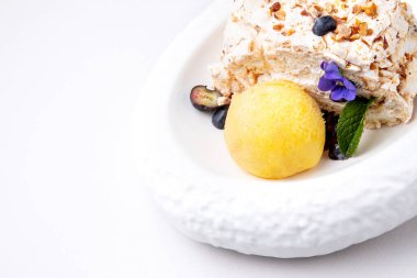 Menekşe ve nane yaprağıyla süslenmiş bir top dondurmalı kremalı tatlı.