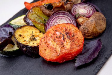 Arka planda siyah bir tabakta ızgara sebze.