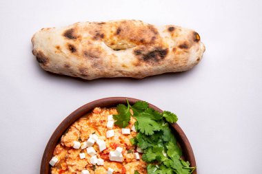 Şifalı bitkilerle, peynirle ve arka planda taze hamur işleriyle Shakuka.