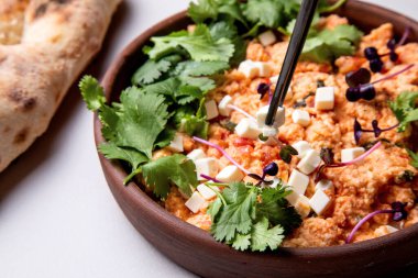 Şifalı bitkilerle, peynirle ve arka planda taze hamur işleriyle Shakuka.