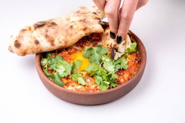 Şifalı bitkilerle, peynirle ve arka planda taze hamur işleriyle Shakuka.