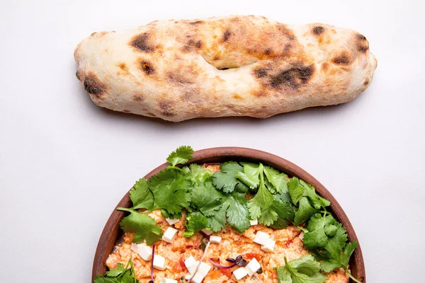 Şifalı bitkilerle, peynirle ve arka planda taze hamur işleriyle Shakuka.